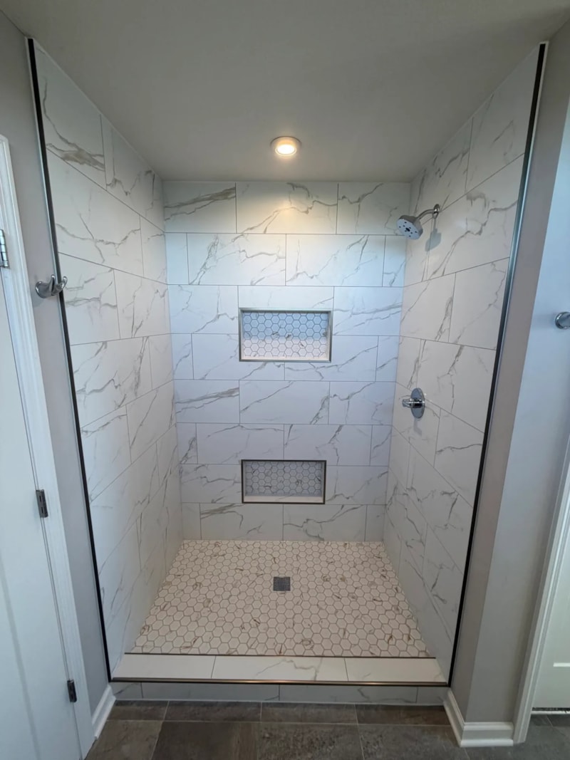 Custom tiled walk-in shower with marble-look porcelain tile and two recessed niches in a Minnetrista bathroom remodel